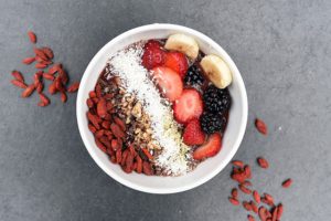 The picture of a bowl of fresh fruits and nuts.