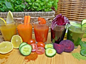 The images of glasses filed with fruit and veggie smoothies, with more fruits and veggies before them.