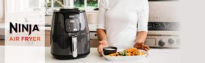 The Picture of a Ninja air fryer sitting on a kitchen counter in front of some amazing dish's of food.