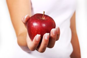 The picture of a woman holding an apple, that is loaded with fiber.