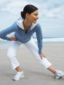 The picture of a woman doing stretch exercises on a beach.