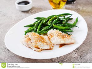 The picture of a deliciuos loking plate of food containing fish and vegetables.